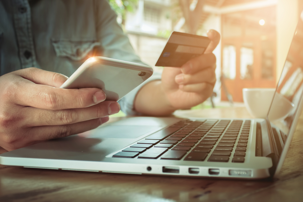 Man's hands holding smartphone and using credit card for online shopping