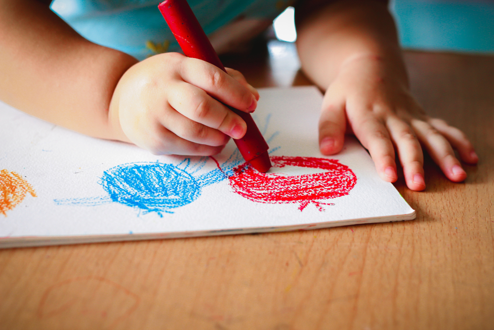 little  girl in blue drawing with colorful crayon