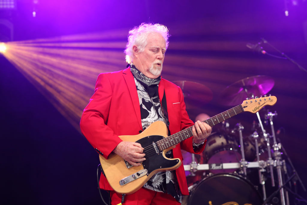 Jim Cregan of Cregan & Co performs on stage in red suit holding a guitar