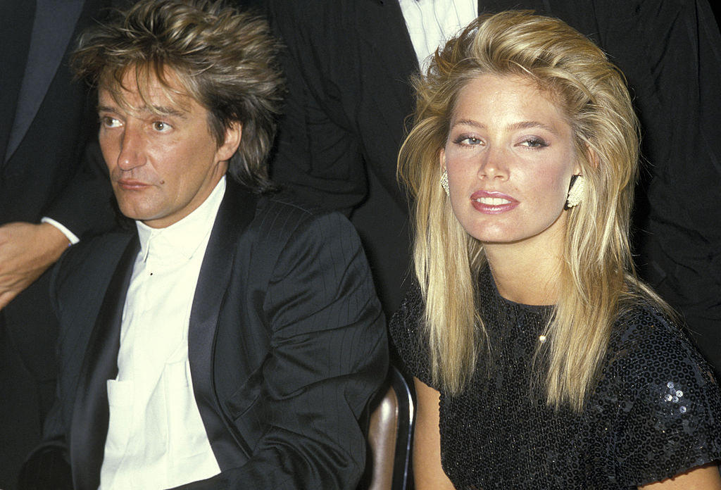 Rod Stewart and Kelly Emberg sitting at a table in formal wear