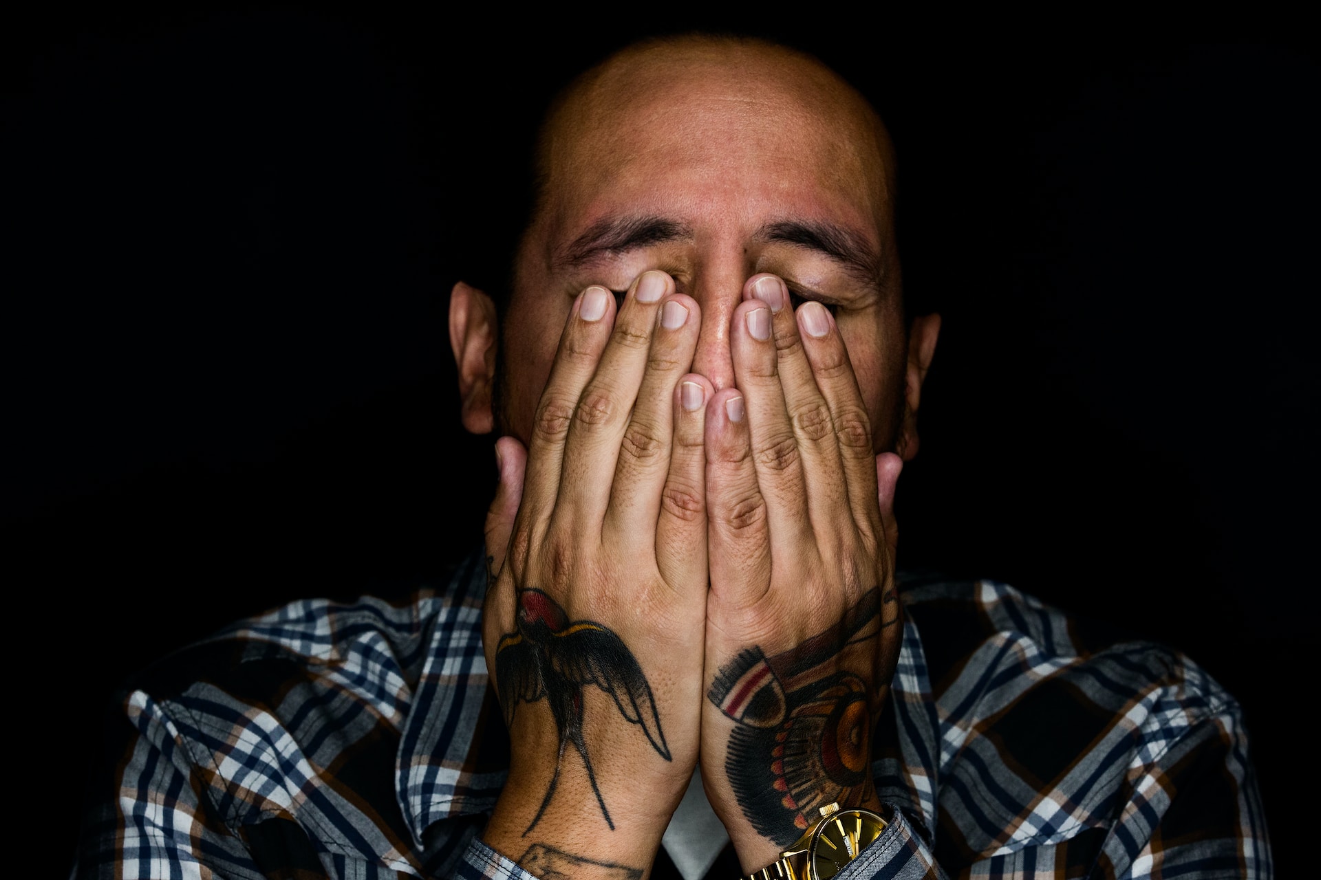 Man covering his eyes with tattoo on his palms