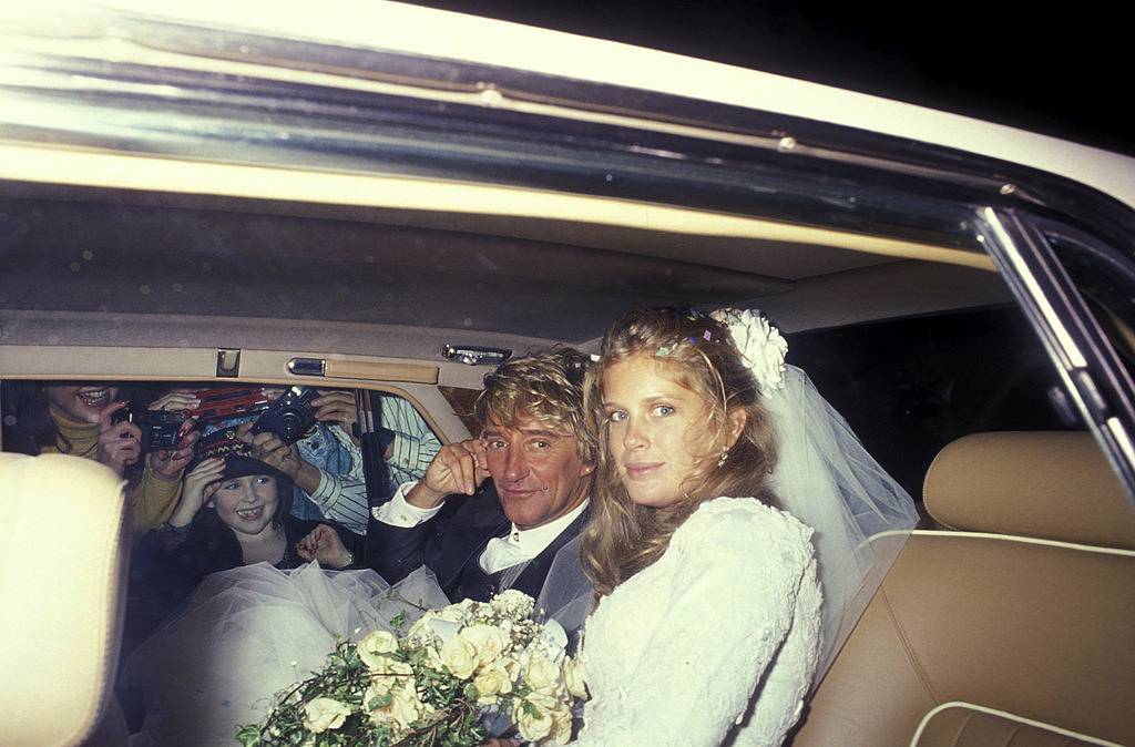 Rod Stewart and Rachel Hunter during their wedding  in a  car looking at the camera