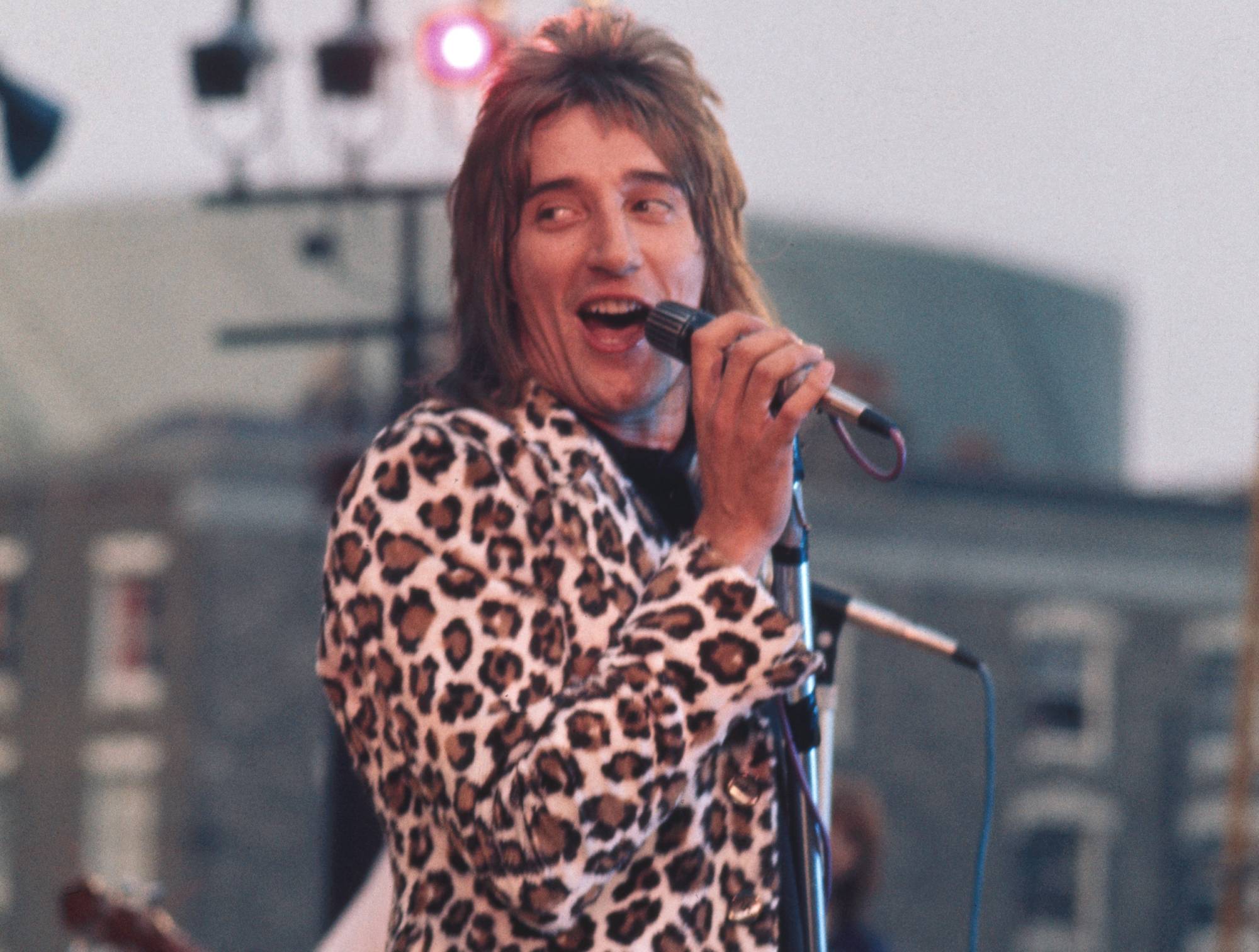 British singer Rod Stewart in concert with the Faces during Rock At The Oval in London in leopard printed jacket singing on a mic