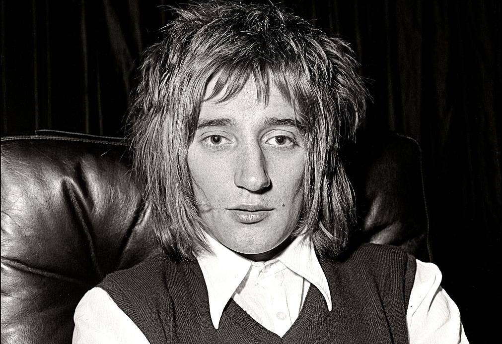 Rod STEWART of The Faces in white shirt and black vest sitting on an armchair