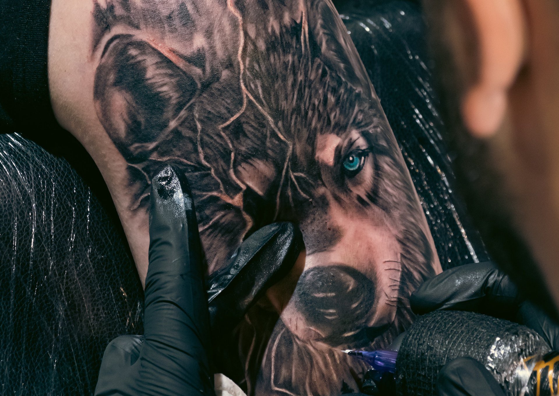 Man in a black tank top getting a wolf tattoo