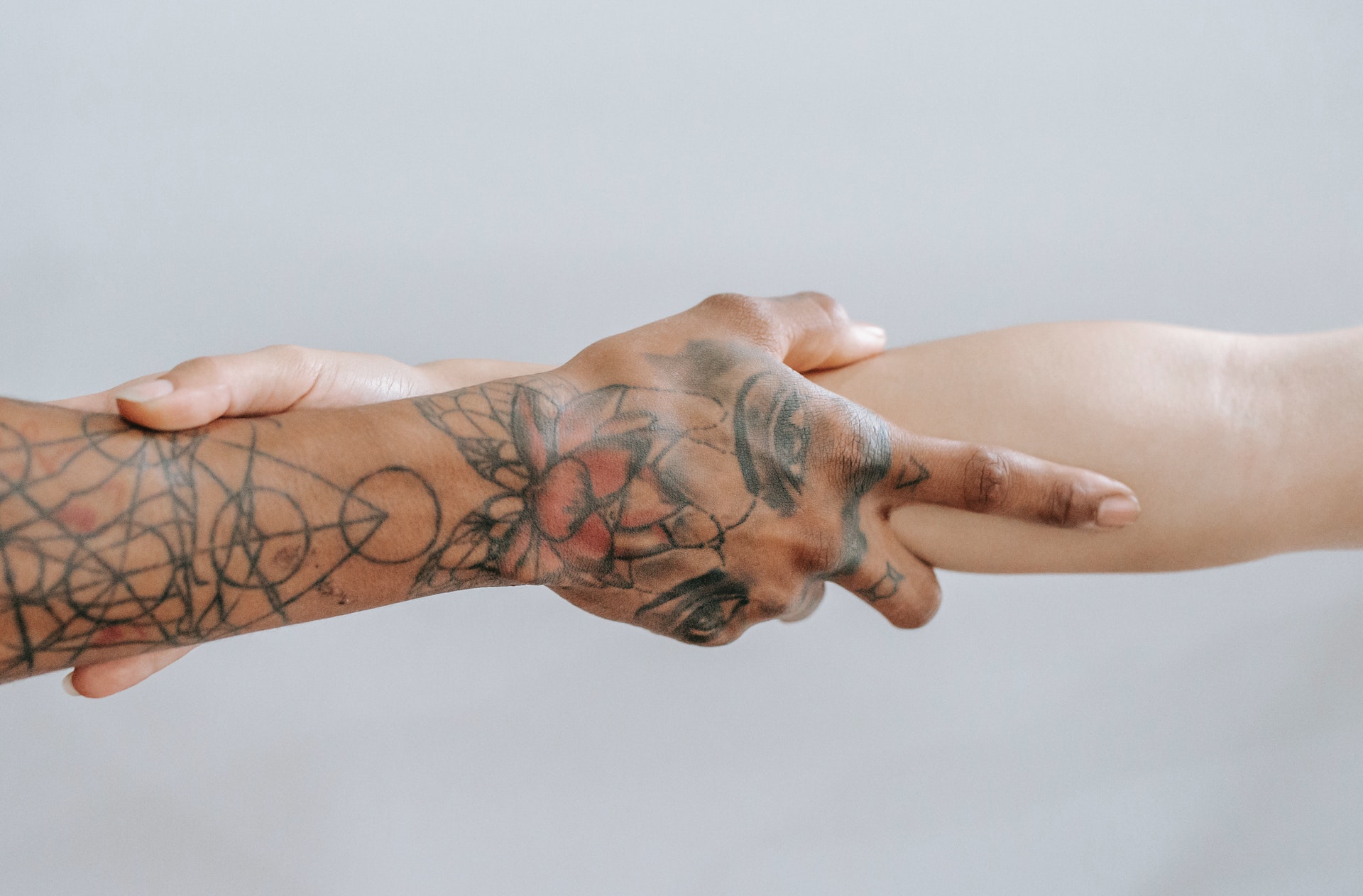 Crop hands with cosmic tattoo holding each other