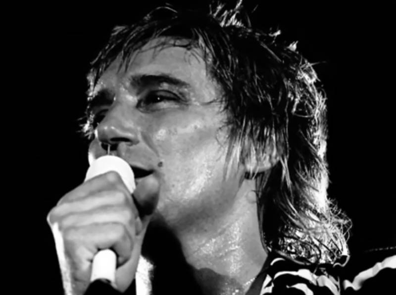 Rod Stewart in concert in Belfast, Ireland in black and white shirt singing on a mic