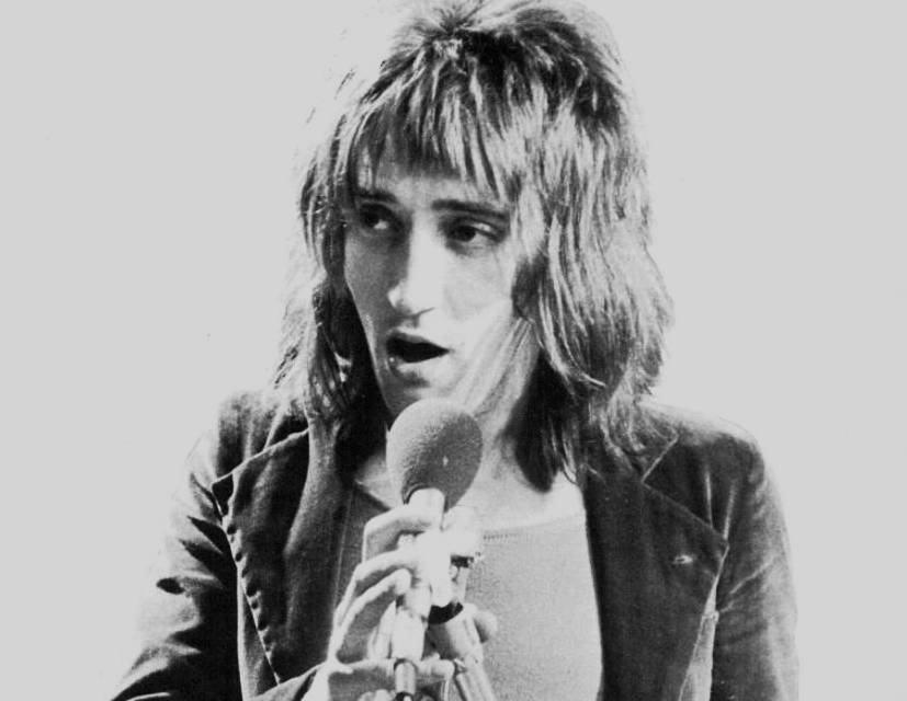 Rod Stewart singing on a mic  wearing a  jacket