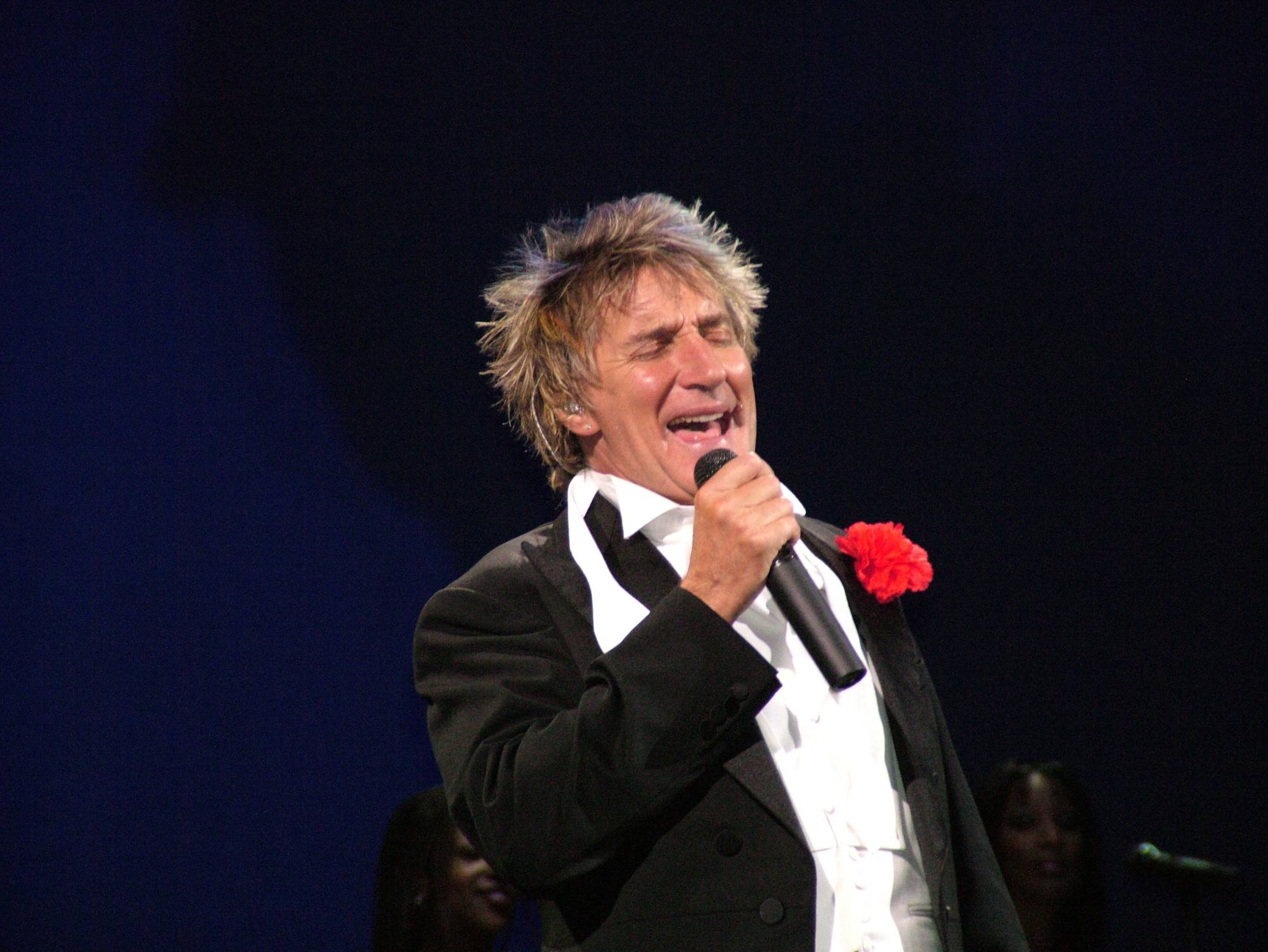 Rod Stewart in black tuxedo  performing on stage