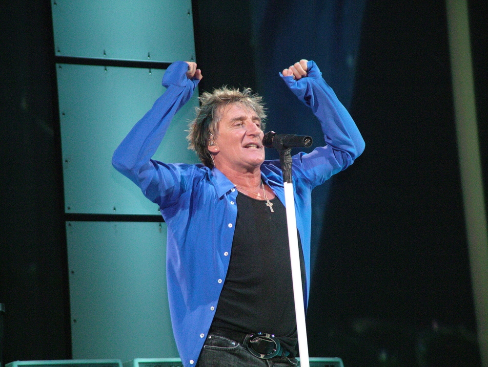 Rod Stewart performing on stage in blue shirt
