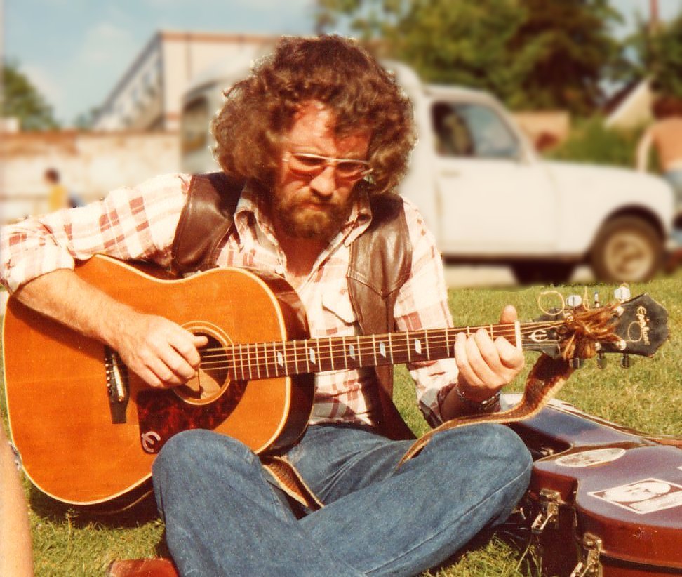 Wizz Jones in plaid shirt playing a guitar