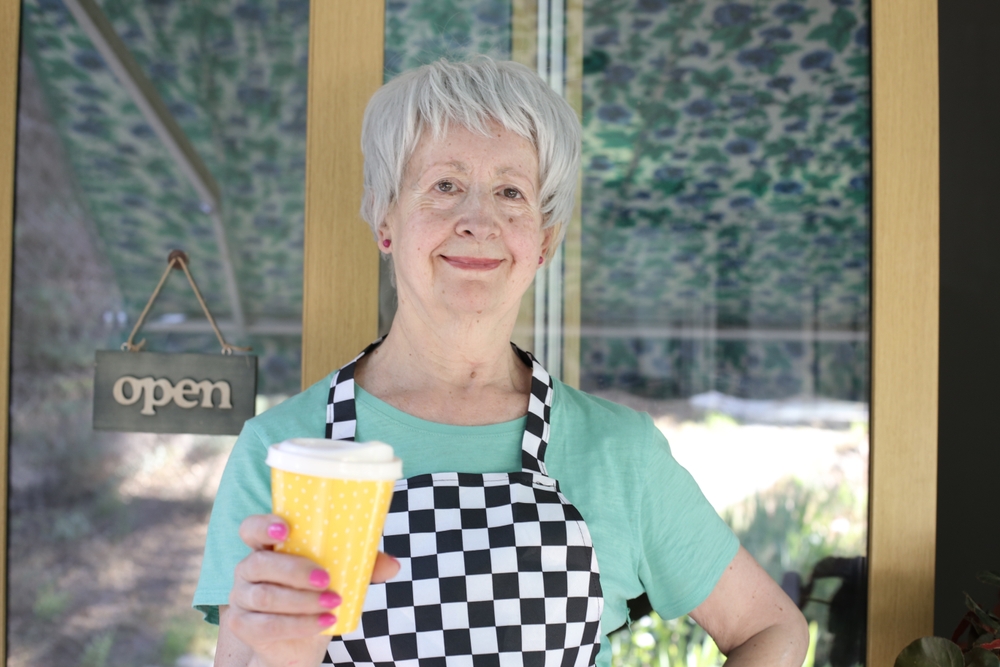 Senior barista woman serving some coffee to go