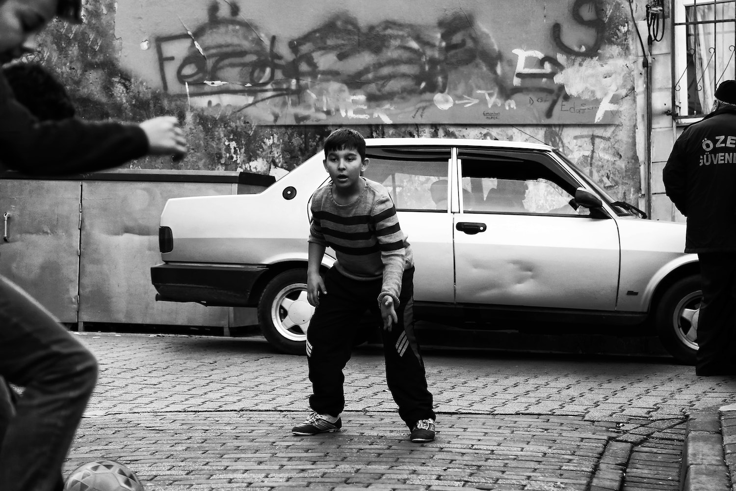 A Boy Playing Soccer Near the Packed Car
