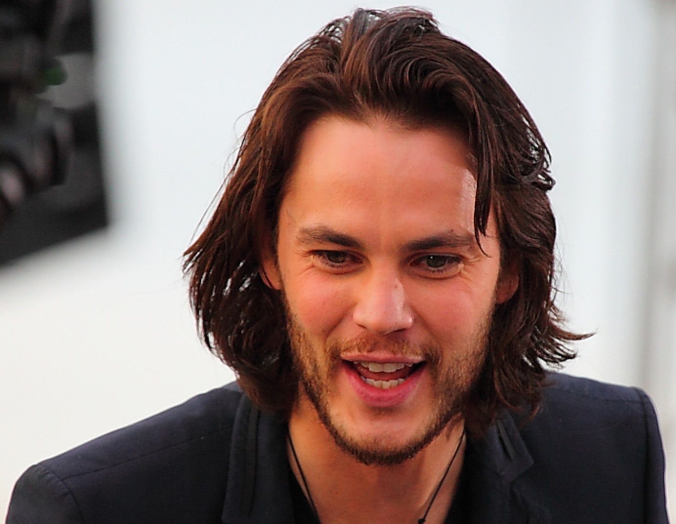 Taylor Kitsch with long hair wearing dark jacket is smiling - 2009