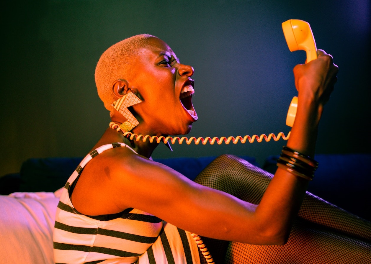 Woman with short hair is screaming to the phone.