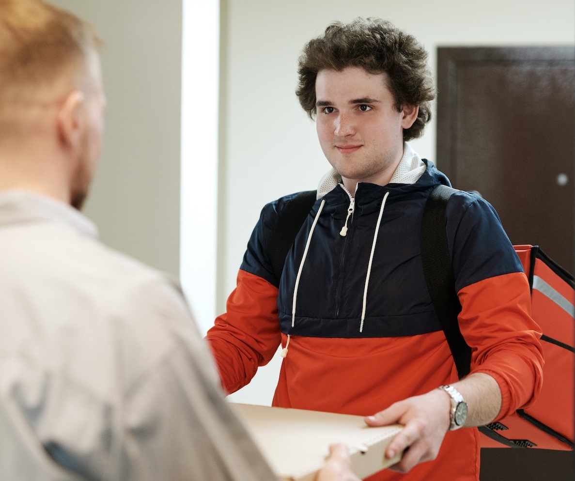 Delivery man is delivering a pizza.