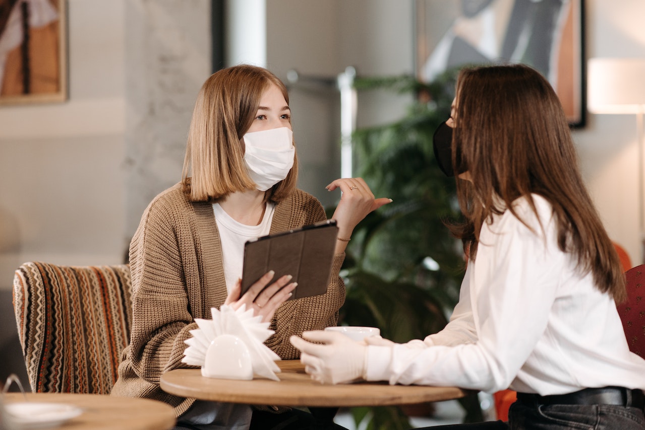 Two woman are talking and making a hand gesture.