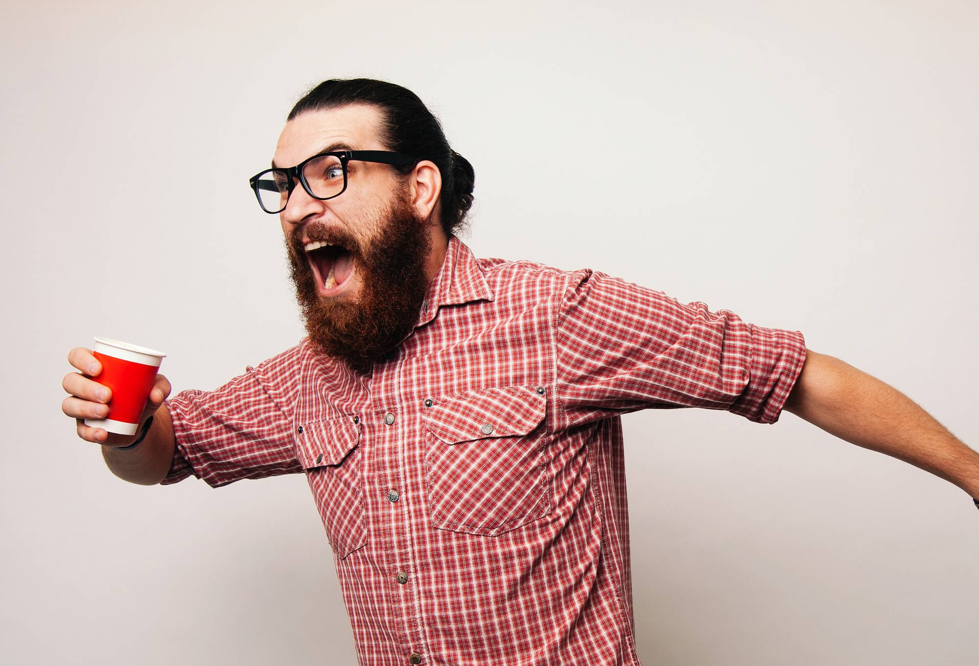 Young bearded man running wearing glasses leaving in hurry to go somewhere