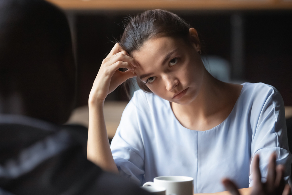 Bored woman on a date sitting at the table looking at her date
