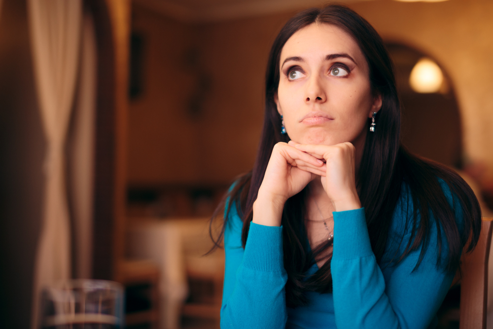 Upset millennial girl in blue top feeling bored at a party or a date