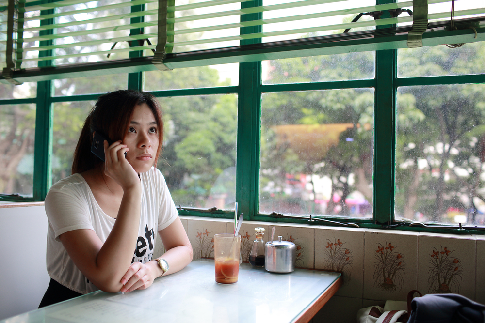 Young girl sitting at a table in a bar drinking