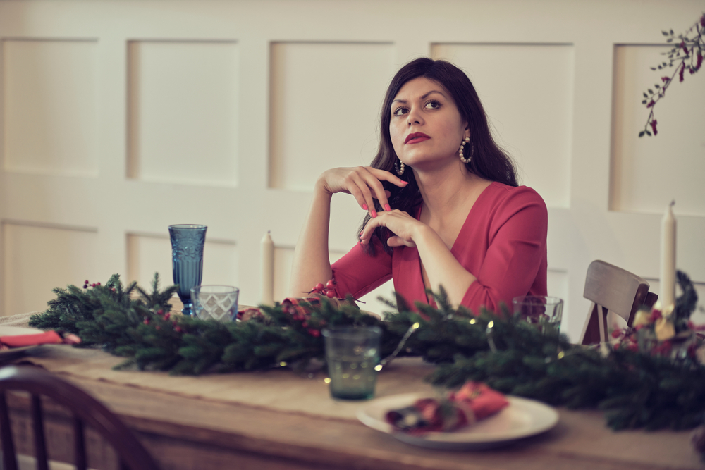 Sad pensive woman sitting at dining table at Christmas in restaurant alone