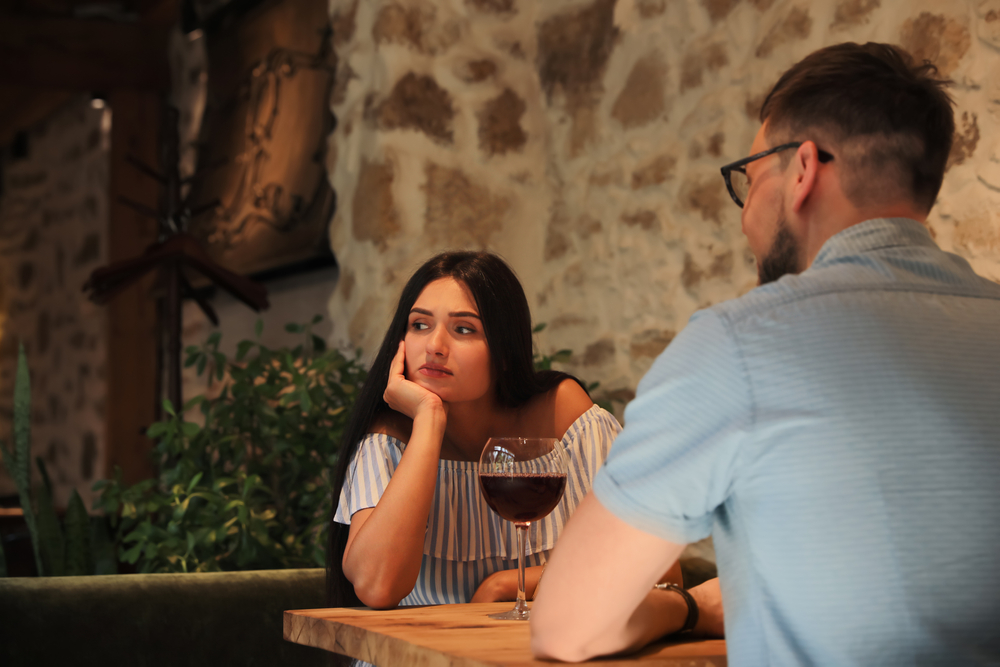 Young woman getting bored during date with man at café