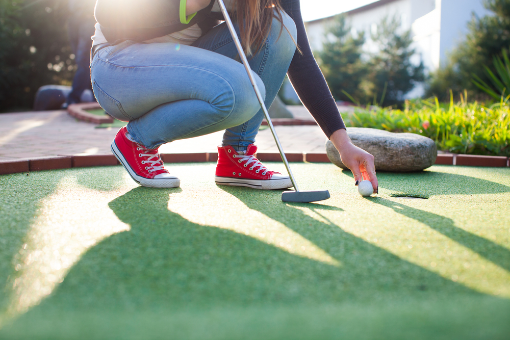Detail of young woman playing mini/adventure golf on a beautiful sunny summer day