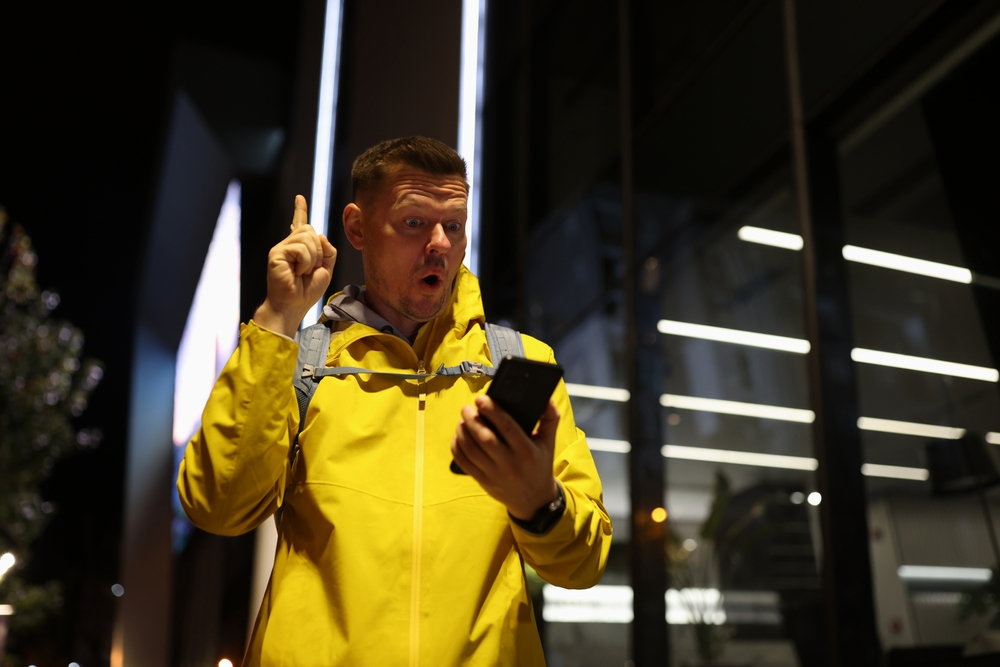 Surprised man looking at his phone at night