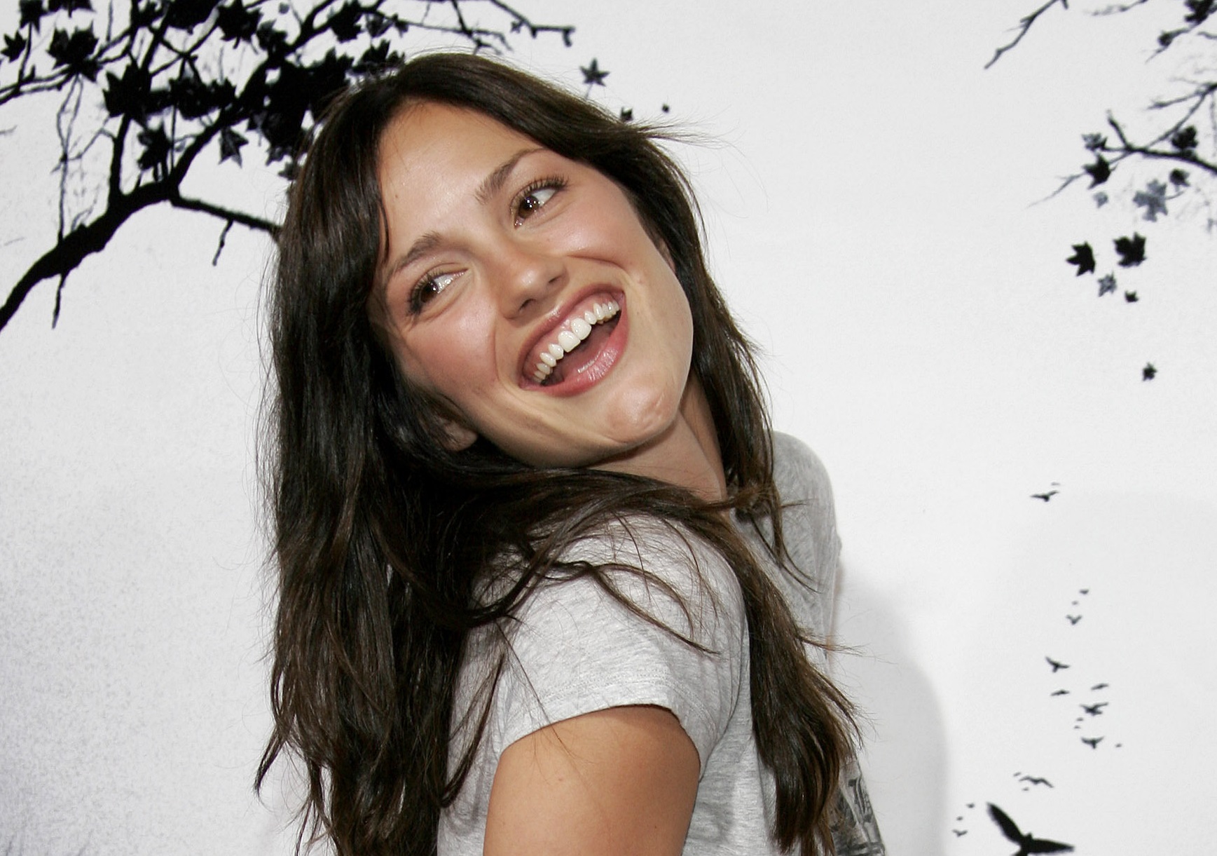 Minka Kelly wearing grey t-shirt is looking at back and smiling - 2007