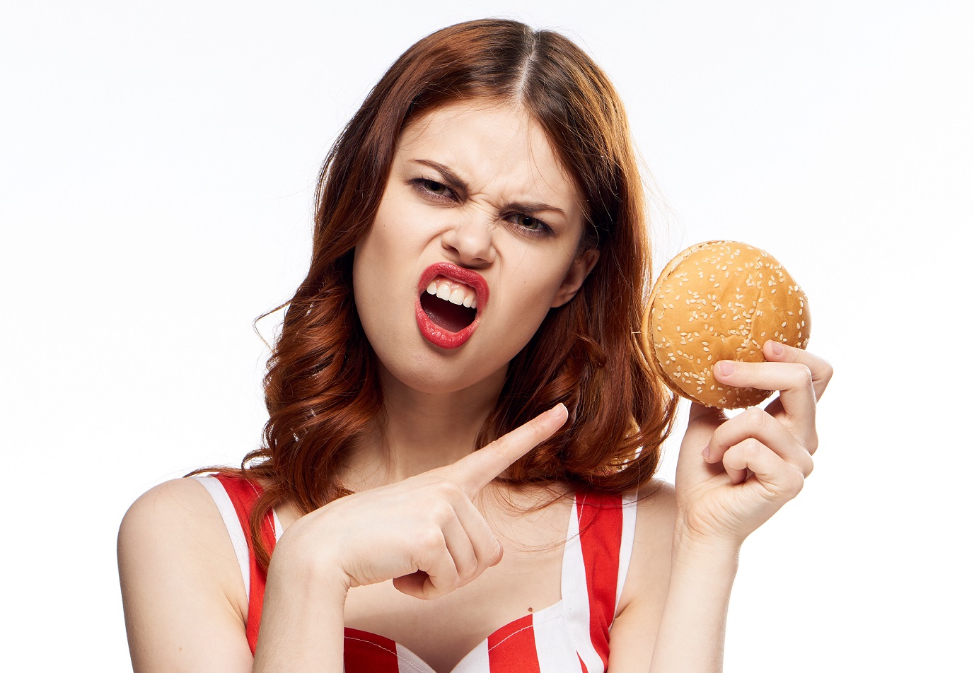Angry woman is making upset face holding a burger.