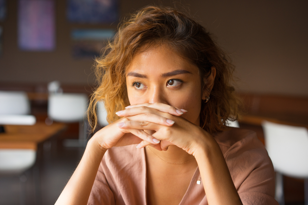 Serious Woman at restaurant covering her mouth with hands looking at something
