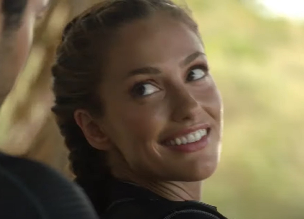 Screenshot: Minka Kelly wearing black shirt is looking at back and smiling - from Charlie's Angels (2011 TV series)