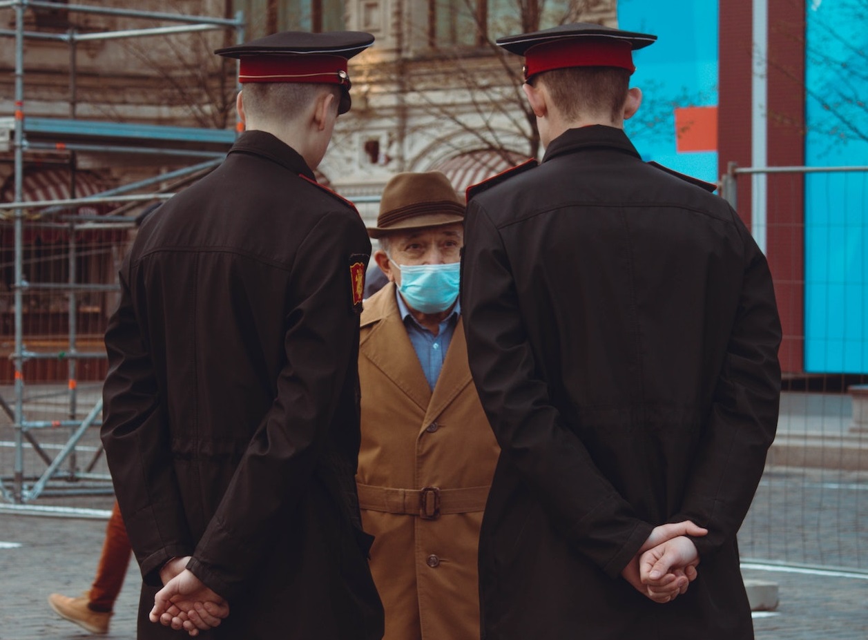 Old man is talking with police officers on street.