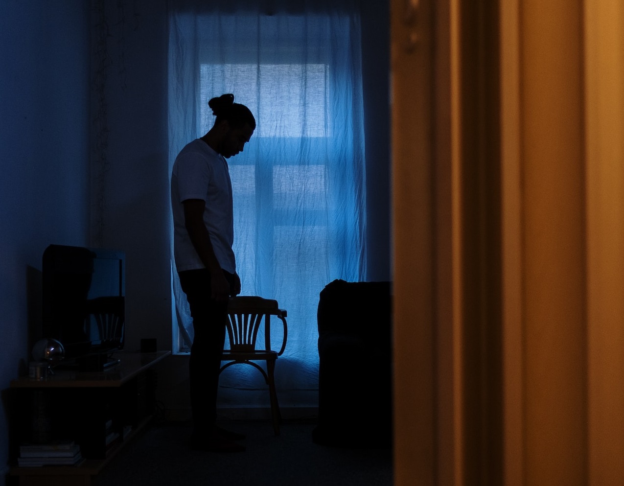 Young man is standing inside of a dark room.