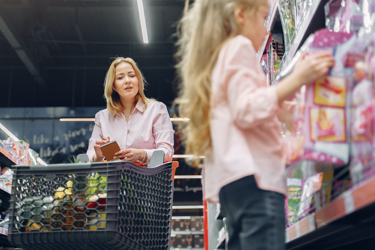 Woman is looking at young girl at store.