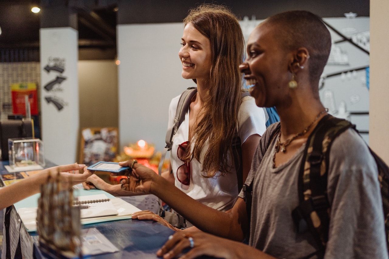 Women receiving a room card at the reception desk.