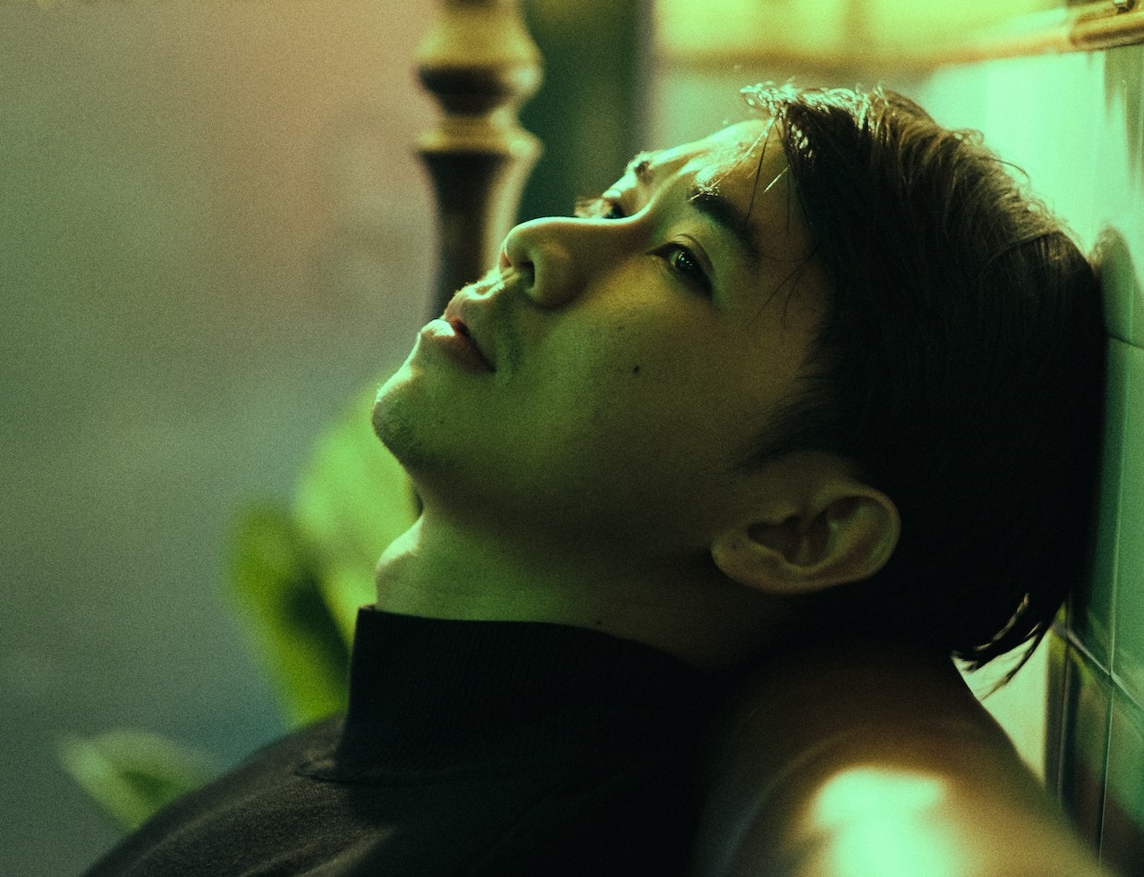 Young man wearing black shirt is looking up and thinking.