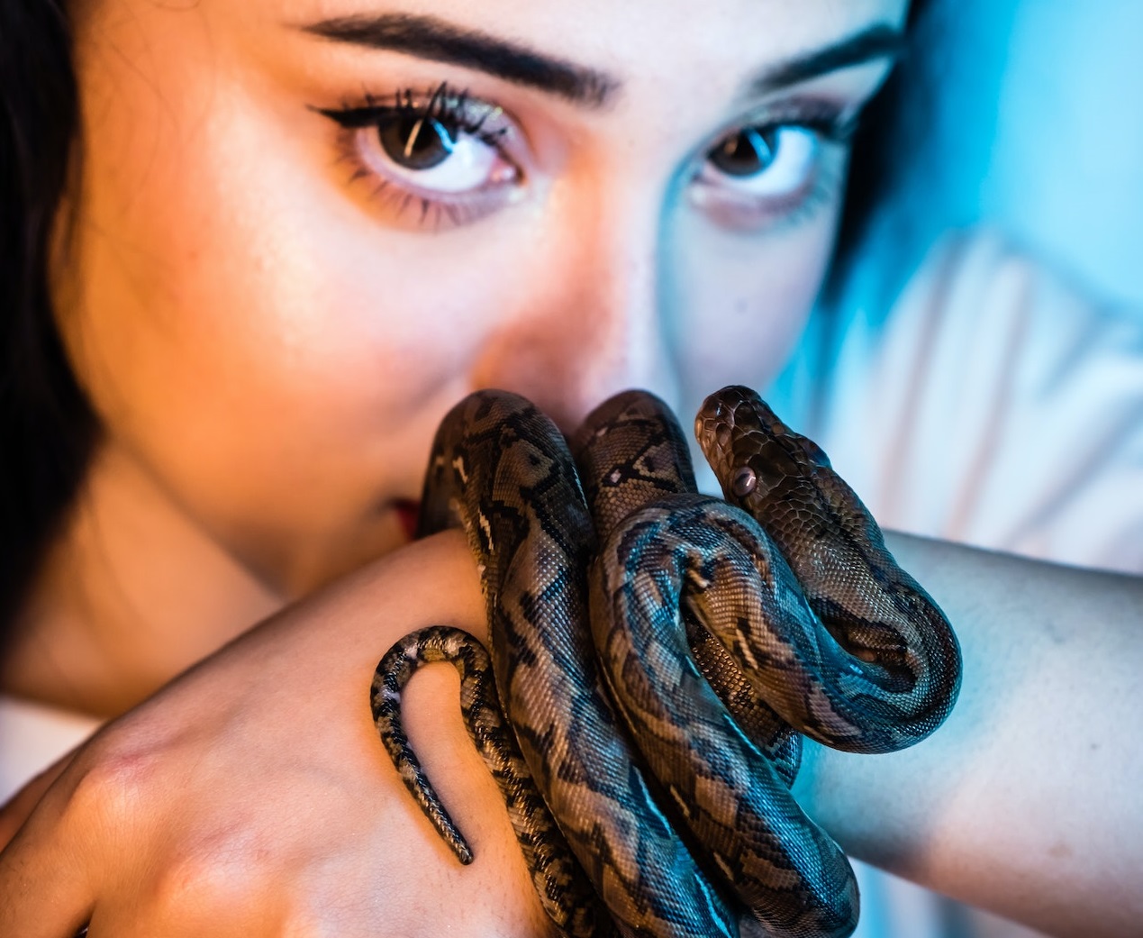 Woman is holding a small snake on her hand.