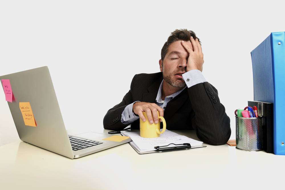 Stressed employee sitting at a desk holding his head