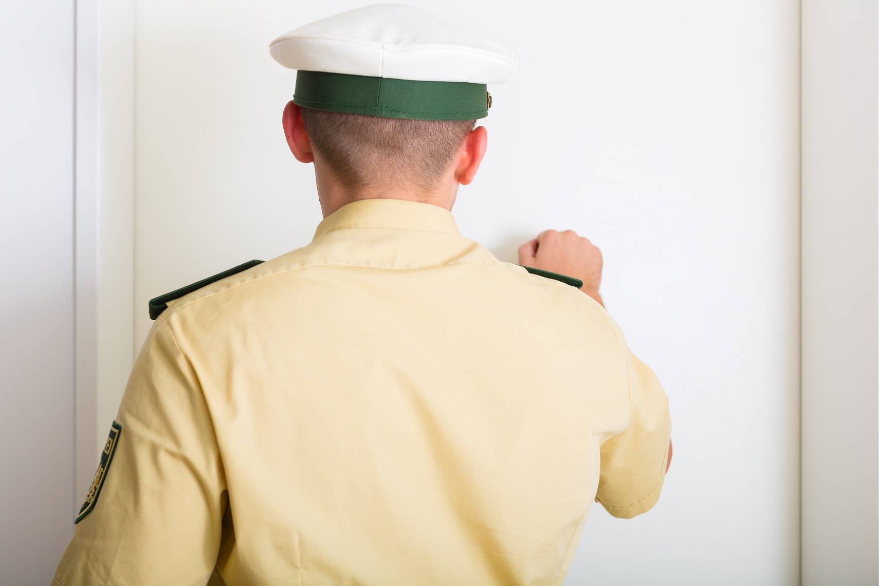 Police officer in uniform is knocking on the front door.