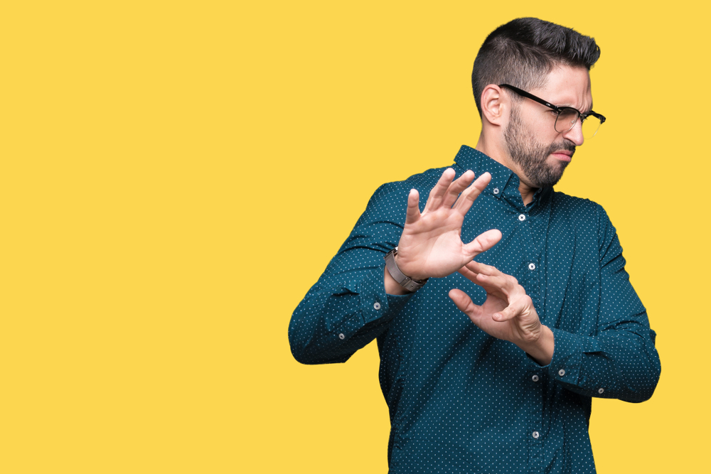 Man with disgusted expression on face holding his hands up looking away from camera