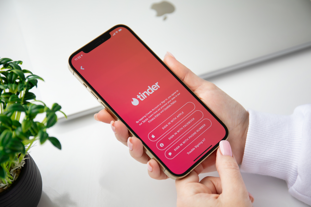 Woman holding a phone with online Internet network service Tinder on the screen