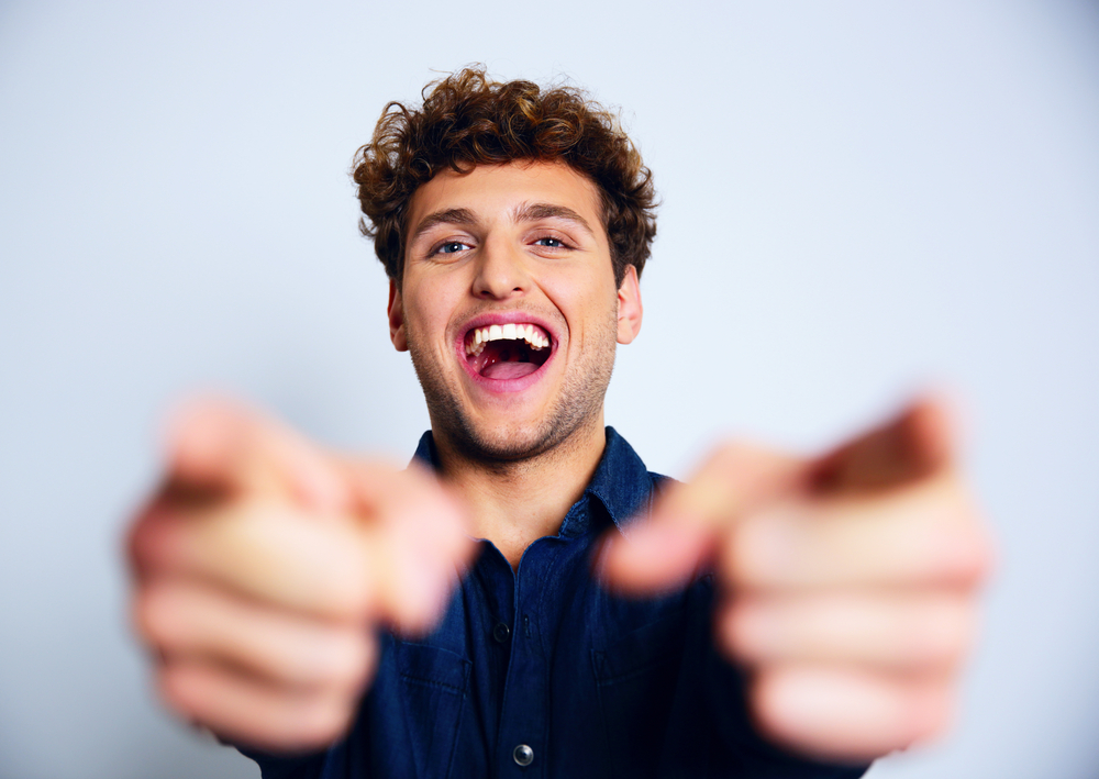 Portrait of a laughing man pointing at the camera with both hands