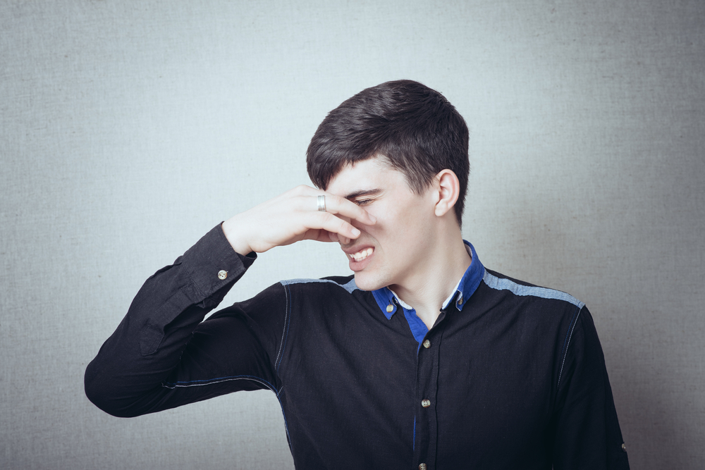 young man closing his nose to avoid bad smell