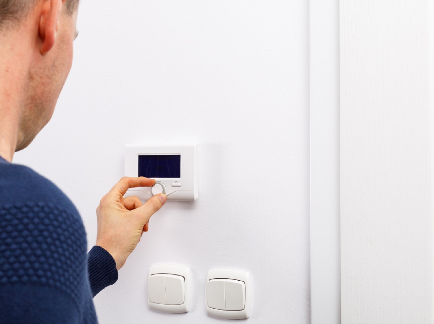 Men regulate temperature on control panel in room.