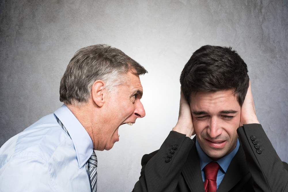 Angry boss shouting to an employee covering his ears