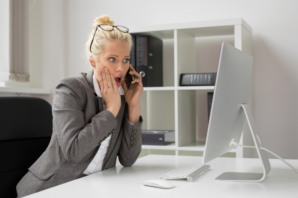 Shocked business woman in office talking on the phone