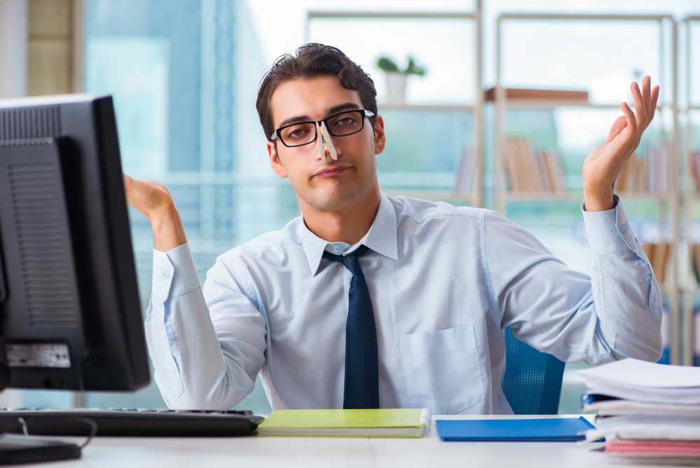 Man closing his nose with a clip because of a bad smell at the office