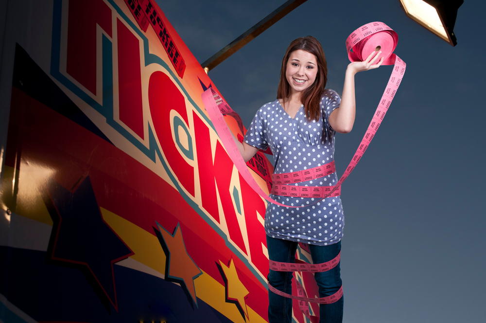 Beautiful young woman, movie theatre employee wrapped in admission tickets